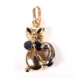 A vintage bi-colour metal and sapphire pendant in the form of a seated Siamese cat.