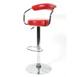 A chrome adjustable bar stool of tubular form upholstered in faux red leather.