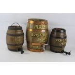 A pair of painted sherry barrels by Moira pottery and a larger wooden coopered barrel.