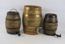 A pair of painted sherry barrels by Moira pottery and a larger wooden coopered barrel.