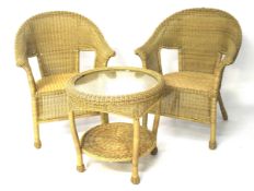 A set of two wicker chairs and a table.