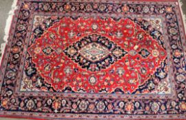 A large floor rug with floral and geometric patterns on a red ground.