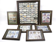 A collection of cigarette and collectors cards mounted in frames.