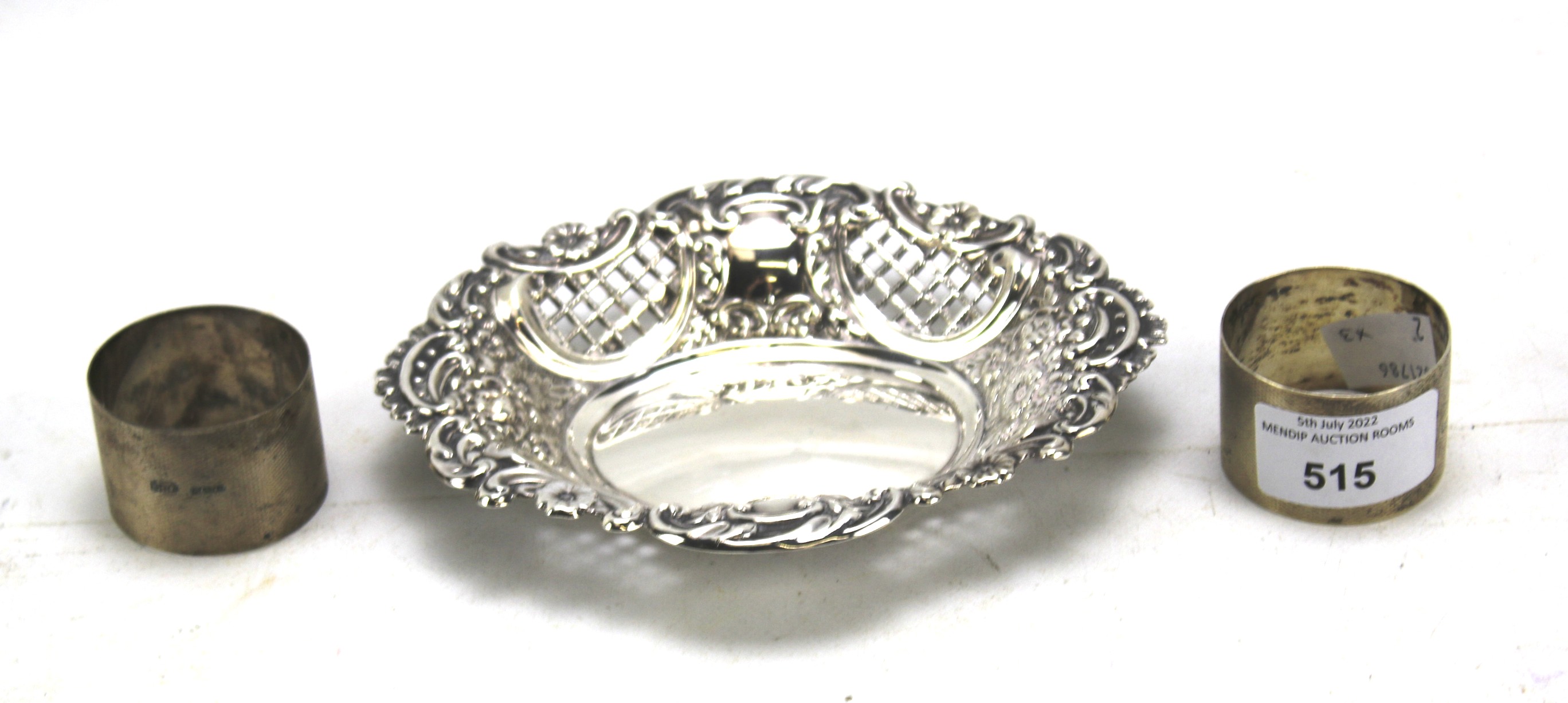 A pair of silver engine turned napkin ring and a pierced shaped oval dish.