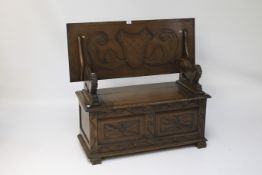 A 20th century monks bench with carved tilt top on lion shaped arms over a storage bench.