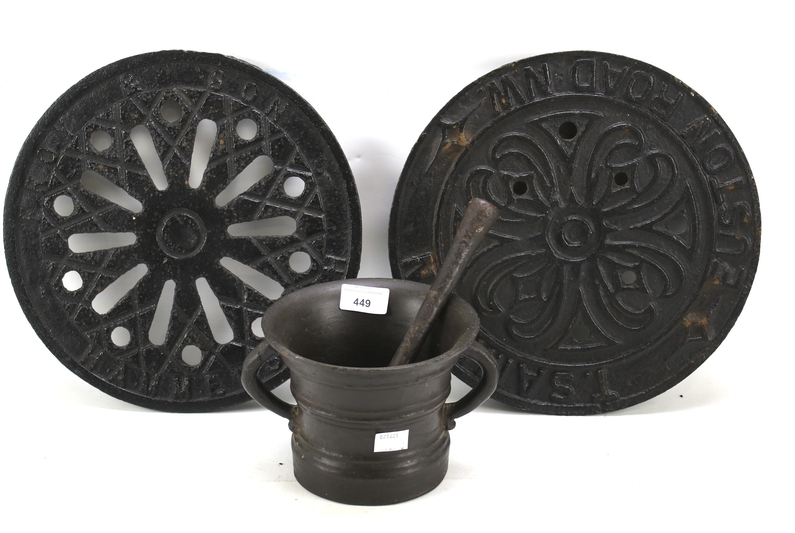 Two cast metal drain covers and a mortar and pestle.