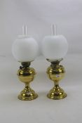 Two early 20th century brass oil lamps with white glass round shades.