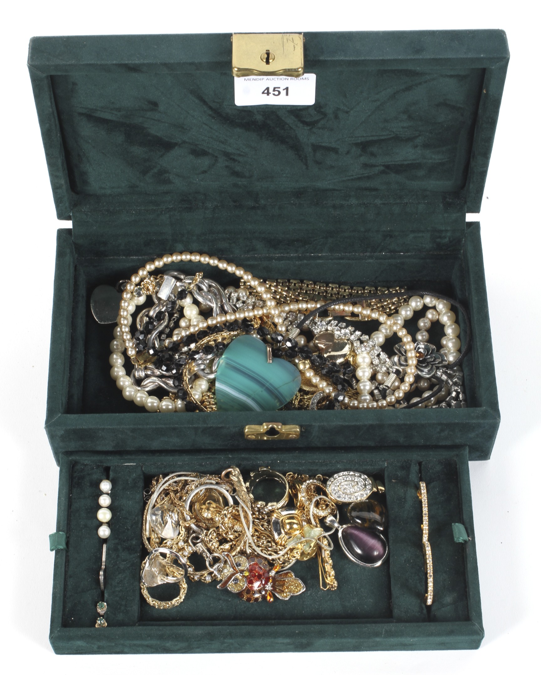 A green velvet box containing an assortment of vintage jewellery.