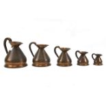 A set of five graduating copper measuring jugs.