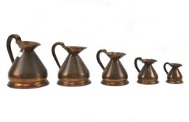 A set of five graduating copper measuring jugs.