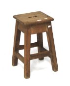 An Arts and Crafts oak stool with central carrying grip.