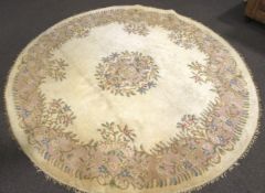 A large cicular room size rug of oriental design decorated with garlands of flowers on a cream