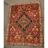 A hand made Eastern floor rug the central medalion on a red ground with geometric patterns 110cm x