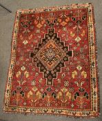 A hand made Eastern floor rug the central medalion on a red ground with geometric patterns 110cm x