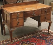 A hardwood kneehole serpentine desk with gallery back.