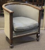 An Arts and Crafts style oak tub chair. With reeded frame, raised on squat bun supports to casters.