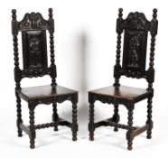 A pair of early 20th century ebonised carved Jacobean style hall chairs.