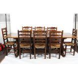 A large 19th century oak plank top trestle dining table and eight rush seated ladderback chairs.