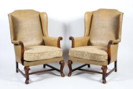 A pair of mid 20th century leatherette winged back elbow chairs with stud work decoration and