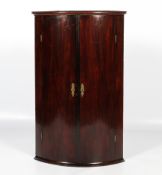 A 19th century mahogany bow fronted two-door wall hanging corner cupboard.