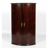 A 19th century mahogany bow fronted two-door wall hanging corner cupboard.