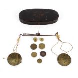 A set of George III travelling pocket scales in black and gilt oval metal case.