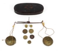 A set of George III travelling pocket scales in black and gilt oval metal case.