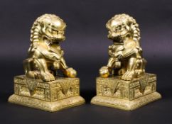A pair of 20th century Chinese gilt-bronze lion dogs on plinth bases.