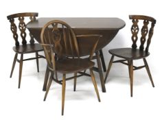 A dark stained oak Ercol dining table and three chairs.