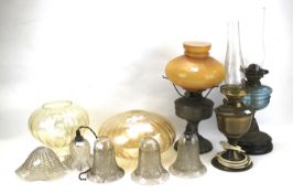 Three oil lamps and early 20th century etched glass shades.