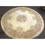 A large circular room size rug of oriental design decorated with garlands of flowers on a cream