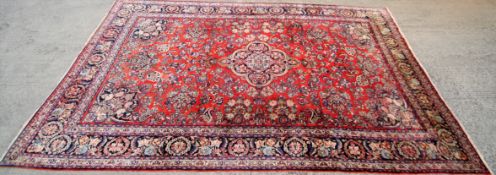 A 20th century wool Persian style carpet with central blue, brown and red medallion.