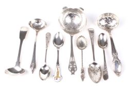 An assortment of silver teaspoons, two sauce ladles and two Victorian sugar sifters.