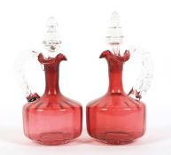 A pair of Victorian cranberry glass claret jugs and stoppers.