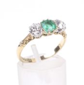 An early 20th century gold, emerald and diamond three stone ring.