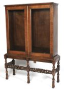 An early 20th century walnut glazed cabinet on stand.