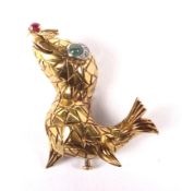 A French gold, ruby, emerald and diamond brooch in the form of a comic seal.