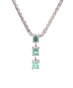 An emerald three stone pendant and chain.
