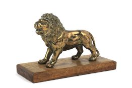 An early 20th century brass model of a lion on wooden stand mounted as a paperweight.