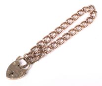 A 9ct Rose gold curb link bracelet with 9ct gold padlock and safety chain.