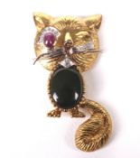 A Chinese gold, ruby, nephrite and diamond brooch in the form of a comic 'winking' cat.