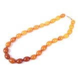 An amber oval bead necklace, the 26 variegated butterscotch-coloured oval beads approx. 16.