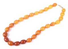 An amber oval bead necklace, the 26 variegated butterscotch-coloured oval beads approx. 16.