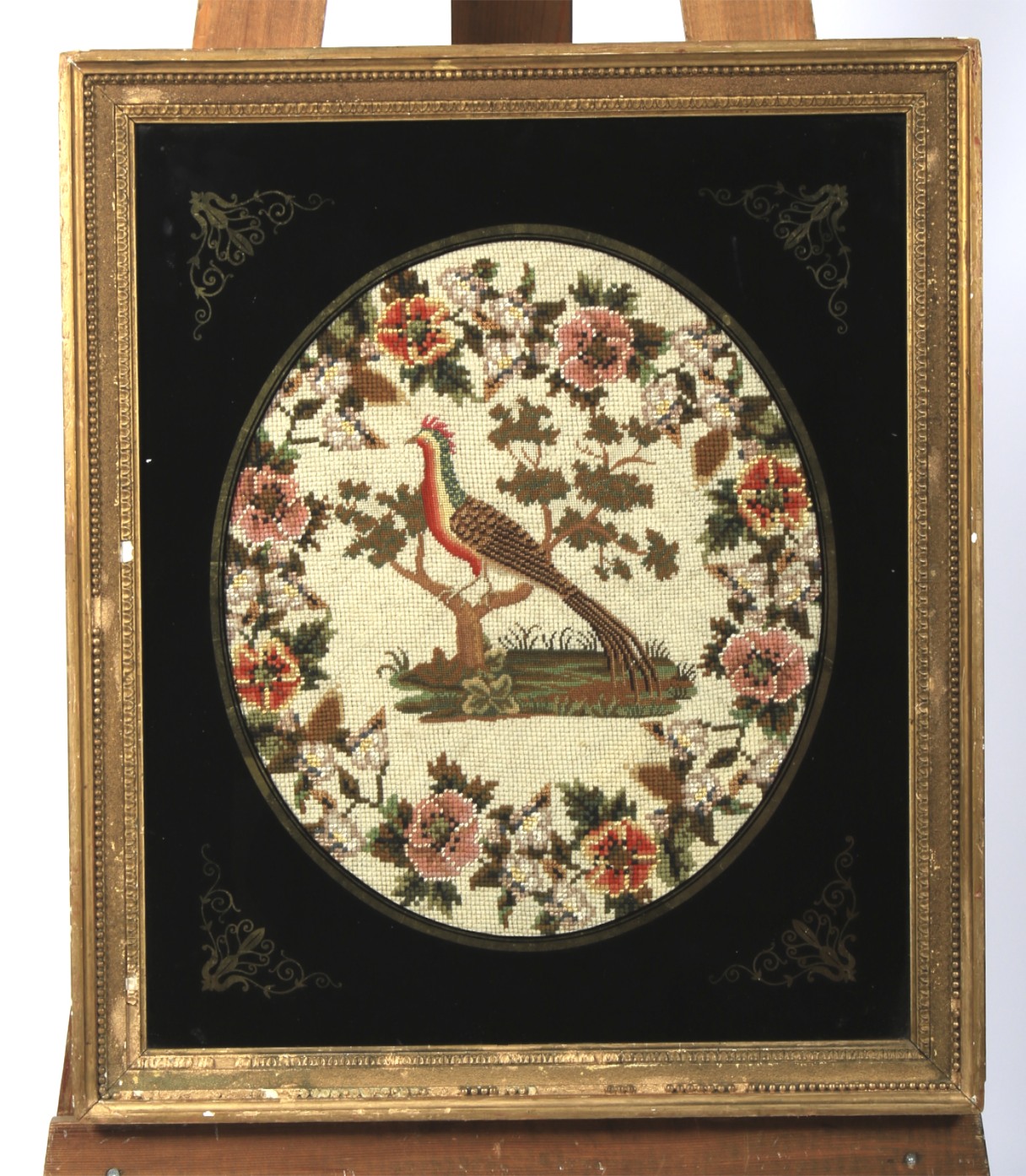 A Victorian needlework in verre eglomise giltwood frame.