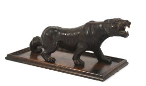 A bronzed resin model of a tiger on a stained oak base.