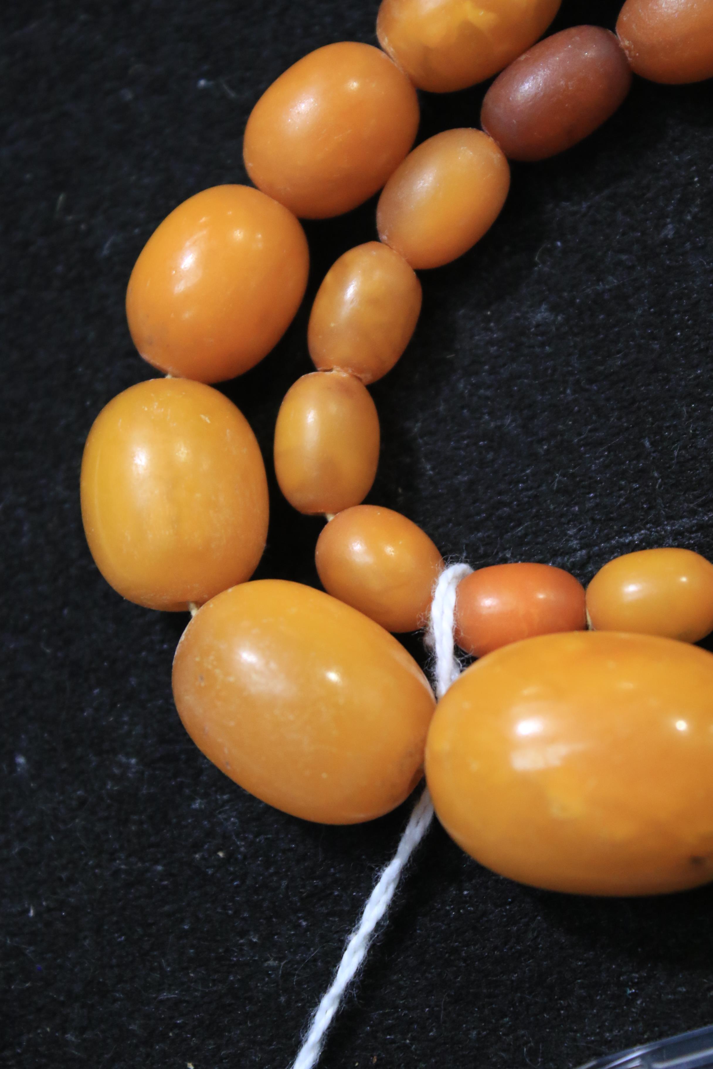 A amber oval bead necklace, the 46 varigated butterscotch-coloured oval beads - Image 6 of 14