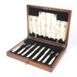 A cased eight setting silver and mother of pearl handled fruit knife and fork set.