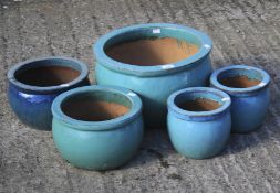 A collection of five assorted glazed terracotta plant pots.