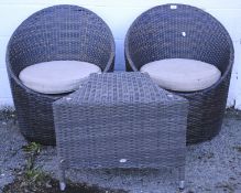 Two modern rattan chairs and a table.