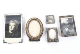 An assortment of minature photo frames including an embossed silver example.